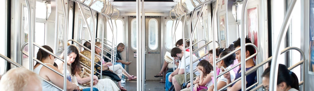 Vagão de trem cheio de pessoas sentadas.